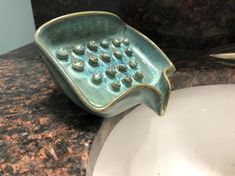 a close up of a ceramic bowl on a counter with a sink in the background