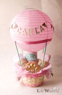 a pink hot air balloon sitting on top of a basket filled with cookies and candy