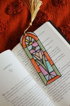 an open book with a stained glass window on it and a tassel hanging from the top