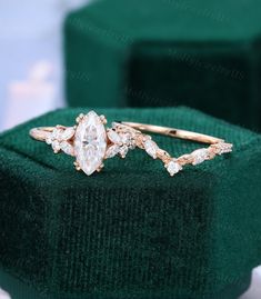 an engagement ring with two diamonds on top of it in a green velvet box next to a pair of gold - plated rings