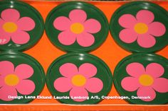 six green and pink plates with flowers painted on the side, sitting in an orange box