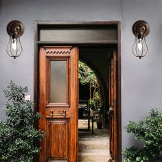 an open door leading to a patio with potted plants on either side and two hanging lights above it