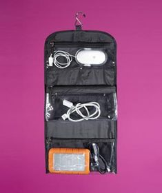 an electronic device hanging on a purple wall with other items in the bag and cords attached to it