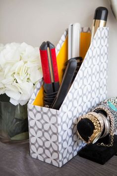 a magazine holder with pens, pencils and other items in it on a table