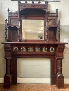 an ornate wooden fireplace mantel with mirror on top