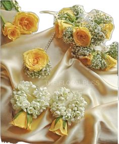 yellow roses and baby's breath flowers are on a white satin fabric with pearls