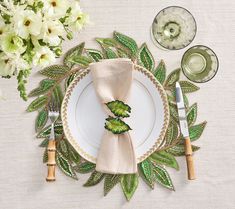 a place setting with napkins, silverware and flowers