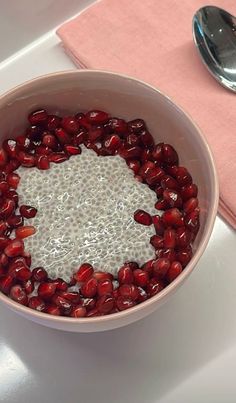 a bowl filled with pomegranates on top of a table next to a spoon