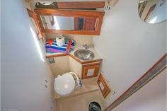 small bathroom with sink, mirror and toilet in the corner on top of stairs leading up to second floor