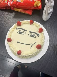 a cake with a face drawn on it sitting on top of a table next to a bag of chips