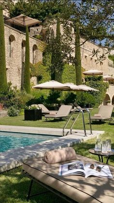 an open book sitting on top of a table next to a pool with lounge chairs and umbrellas