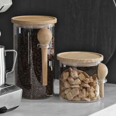 two glass containers filled with dog food next to a coffee grinder and measuring cup