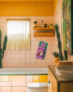 a bathroom with cactus plants and yellow tiles on the walls, along with a white toilet