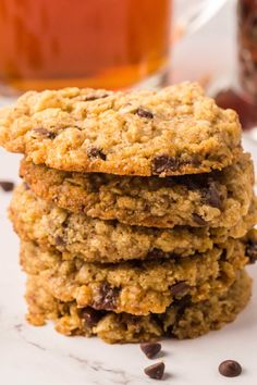 three oatmeal cookies stacked on top of each other next to a glass of tea