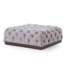 a grey ottoman with buttons on the front and back legs, sitting against a white background