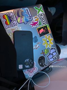 an open laptop computer sitting on top of a table covered in stickers and decals