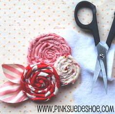 a pair of scissors sitting on top of a piece of fabric next to some flowers