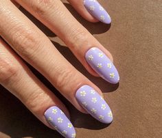 a woman's hand with purple and yellow flowers painted on it, next to her manicured nails