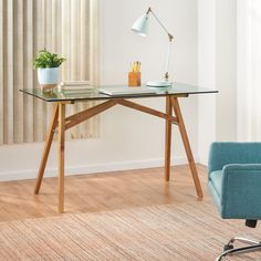 a desk with a chair, lamp and potted plant on it in front of a window