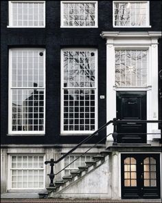 a black and white building with stairs leading up to the front door that has glass panes on it