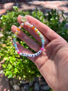 a hand holding a beaded bracelet with the word marfee written on it