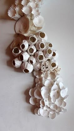 there are many vases made out of clay flowers on the wall, and one is white