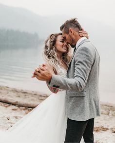 a bride and groom hugging on the beach