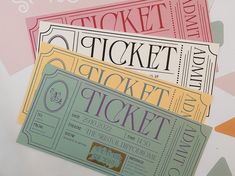 three tickets sitting next to each other on top of a white table with pink, yellow and green paper