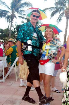 two people are standing under umbrellas in the rain at an outdoor event with other people and palm trees behind them