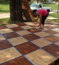 a woman in pink shirt standing on top of a wooden floor next to a tree