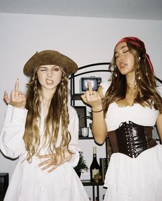 two women dressed in costumes standing next to each other holding up their fingers and making the peace sign