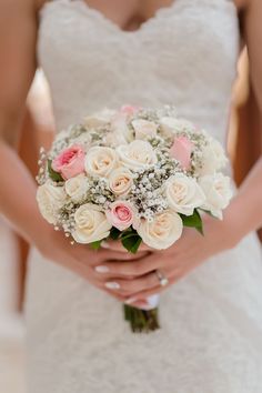 a bride holding a bouquet of white and pink roses