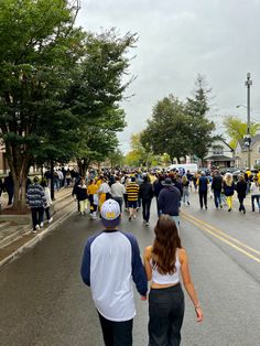 two people walking down the street in front of a crowd