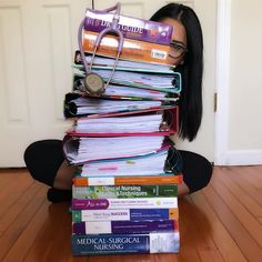 a woman is sitting on the floor with stacks of books and a stethoscope