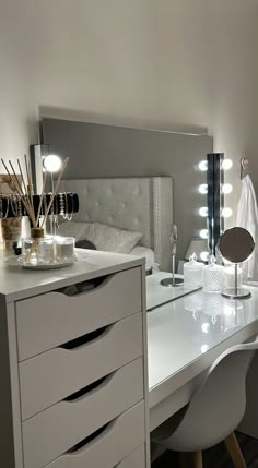 a white desk topped with a mirror and lots of drawers next to a bed in a room