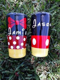 two personalized mickey and minnie tumbles sitting in the grass with their names painted on them