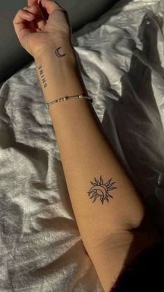 a woman's arm with a small sun and moon tattoo on her left arm