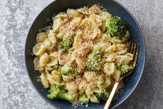 a bowl filled with pasta and broccoli covered in parmesan cheese