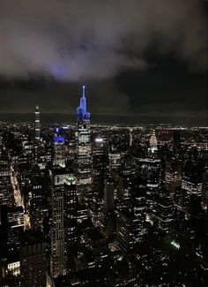 an aerial view of new york city at night with the empire building lit up in blue