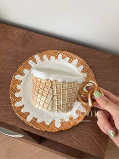 a person is holding a pretzel in front of a cup on a plate