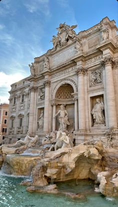 a fountain with statues and lights in front of a building