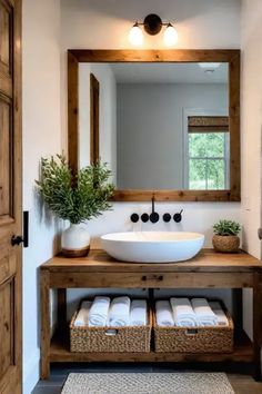 a white sink sitting under a mirror next to a wooden shelf with baskets on it