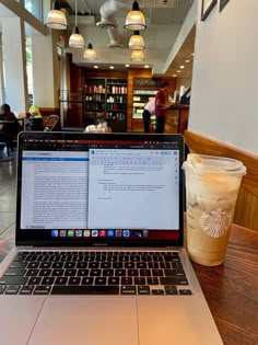 an open laptop computer sitting on top of a wooden table next to a cup of coffee