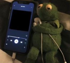 a stuffed animal is next to a cell phone with headphones in its mouth and ear buds out