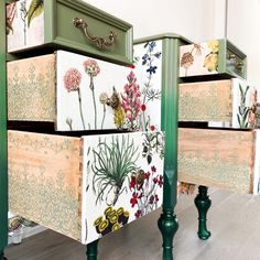 three drawers with flowers painted on them and green legs are sitting in front of each other