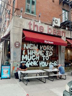 two men sitting on benches in front of the bean new york high school, much to thank you for