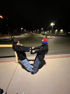 two people holding hands while sitting on a bench in the middle of an empty parking lot