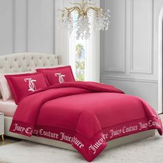 a bed with pink comforter and pillows in a room next to a chandelier