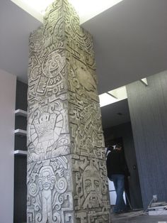 an intricately carved column in the middle of a building with people standing around it