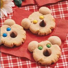 three decorated cookies on a red and white checkered table cloth with flowers in the background